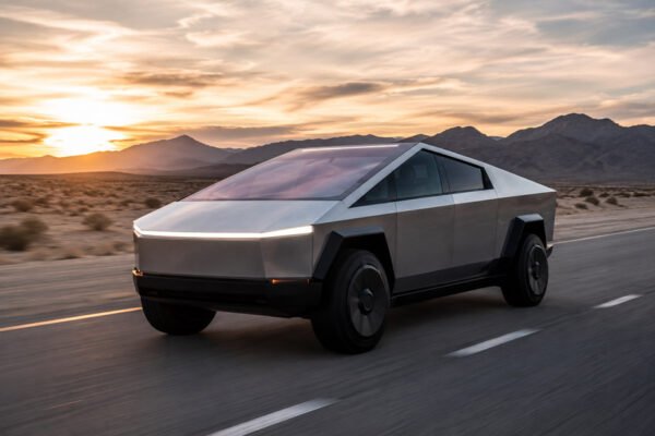 Tesla Cybertruck futuristik melaju di jalan terbuka dengan desain modern dan teknologi kendaraan listrik.